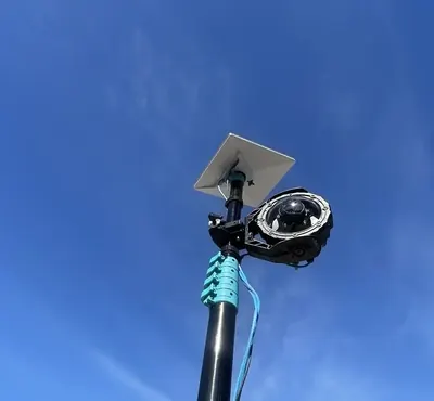 Portable mast with camera and antenna against a clear sky